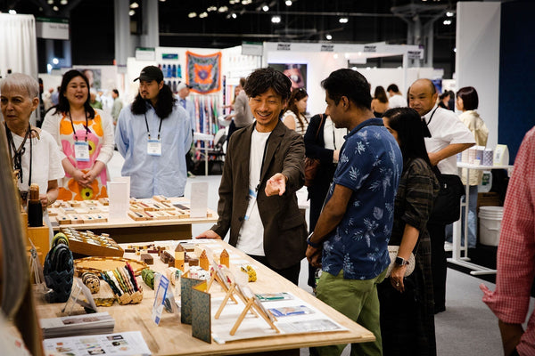 NY NOW会場の手神ブースで、池谷がバイヤーに木工製品を説明している様子