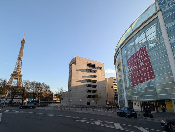 青空にそびえ立つエッフェル塔と、そのほど近くに位置する近代的な外観のパリ日本文化会館の風景。