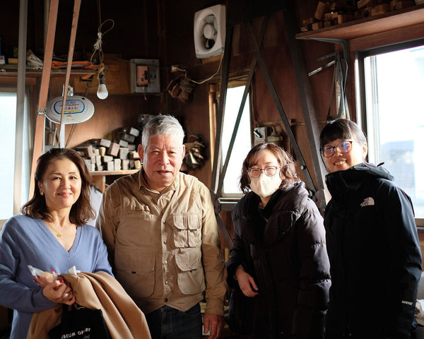 木工所で並んで笑顔で立つ、斎藤との集合写真。