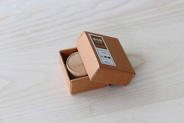 切手モチーフのラベルが貼られた赤茶色のクラフト紙パッケージと、豆茶器のケース。